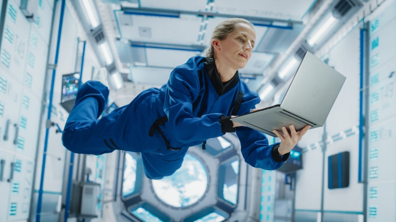 Female Astronaut Using a Laptop in Space Inside a Spacecraft.