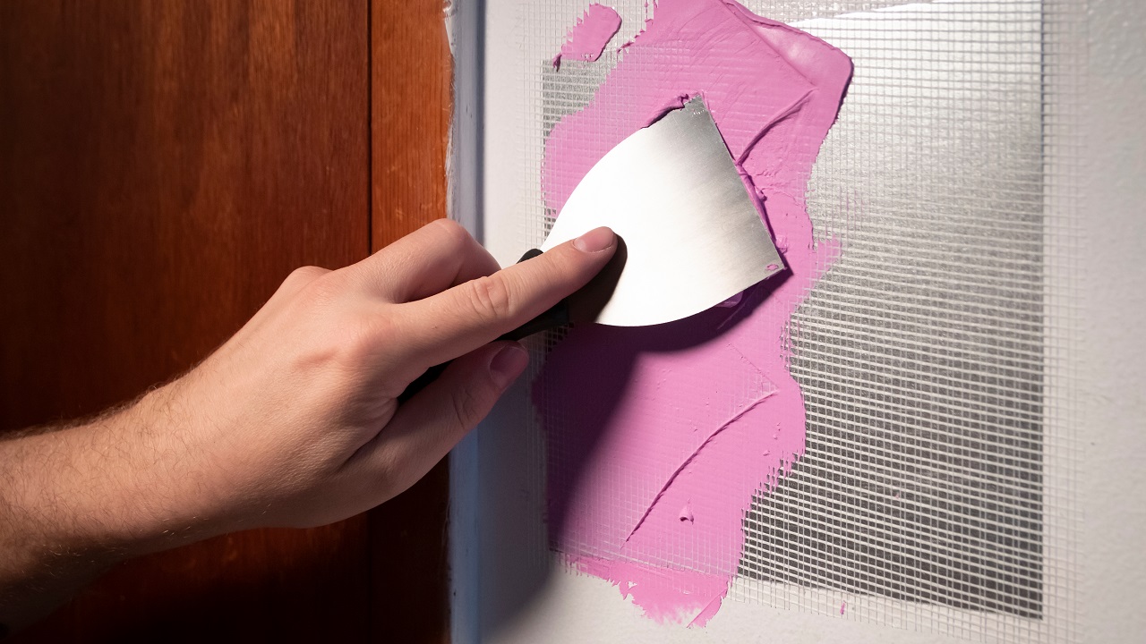 Putty knife application of spackling compound or damaged drywall patch