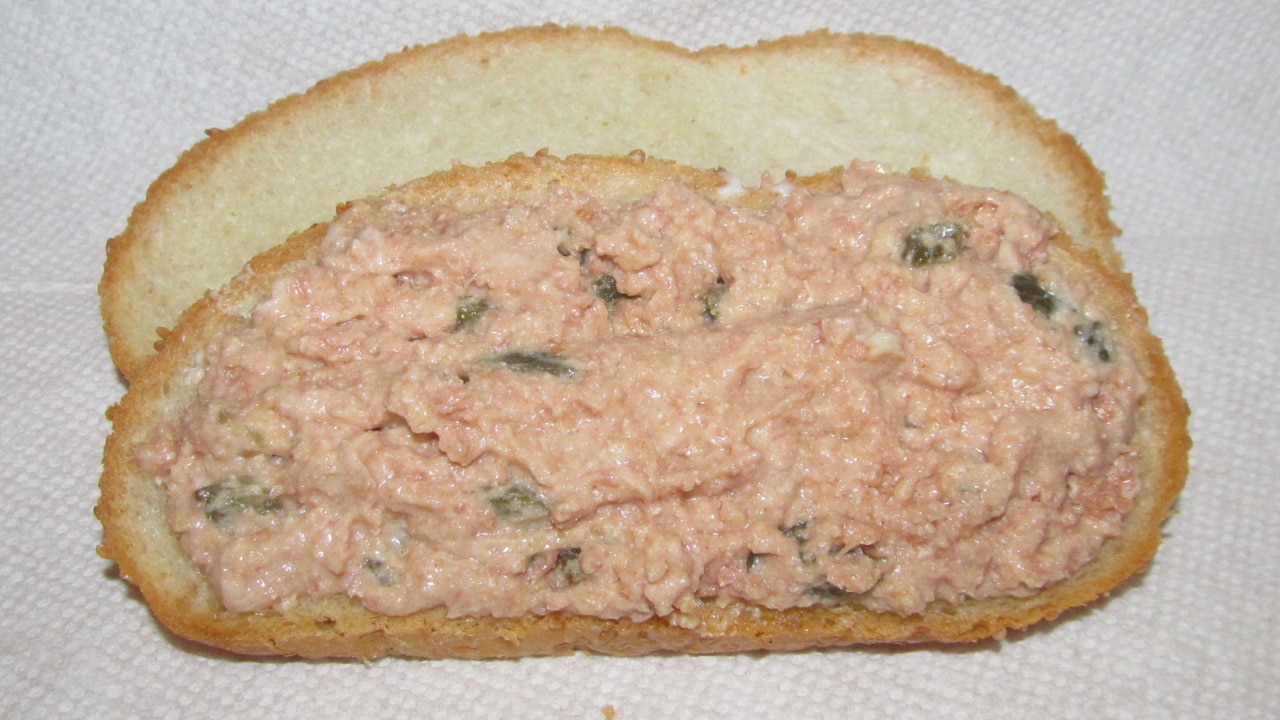 A white bread ham salad sandwich on traditional dish (paper towel)