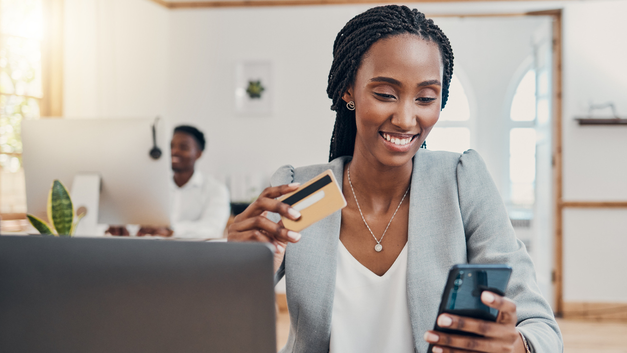 A happy woman paying bills with credit or debit card in hand
