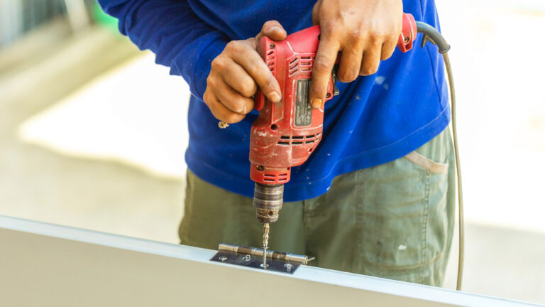 Using a power drill to sink screws into a new door hinge