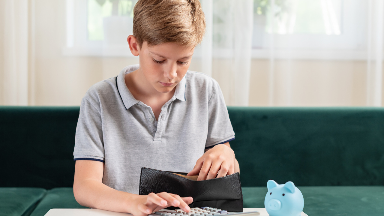 A teen or child looking through wallet, counting coins next to a piggy bank