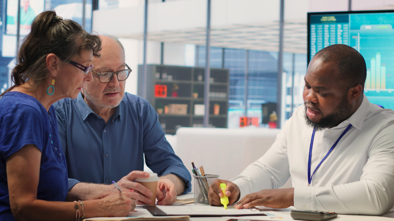 A financial planner or advisor helps two clients break down paperwork line-by-line