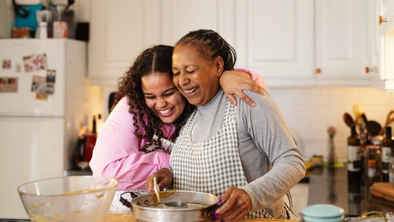 Happy african-american mother and daughter preparing a homemade dessert. They look very happy and joyful to be spending time together. Cooking, homemaking, dinner, family time, quality time, mother and daughter, positive influence, family bonding, feminine energy, black women, young and older, millennial and baby boomer, middle-aged woman, baking, cooking, preparing food.