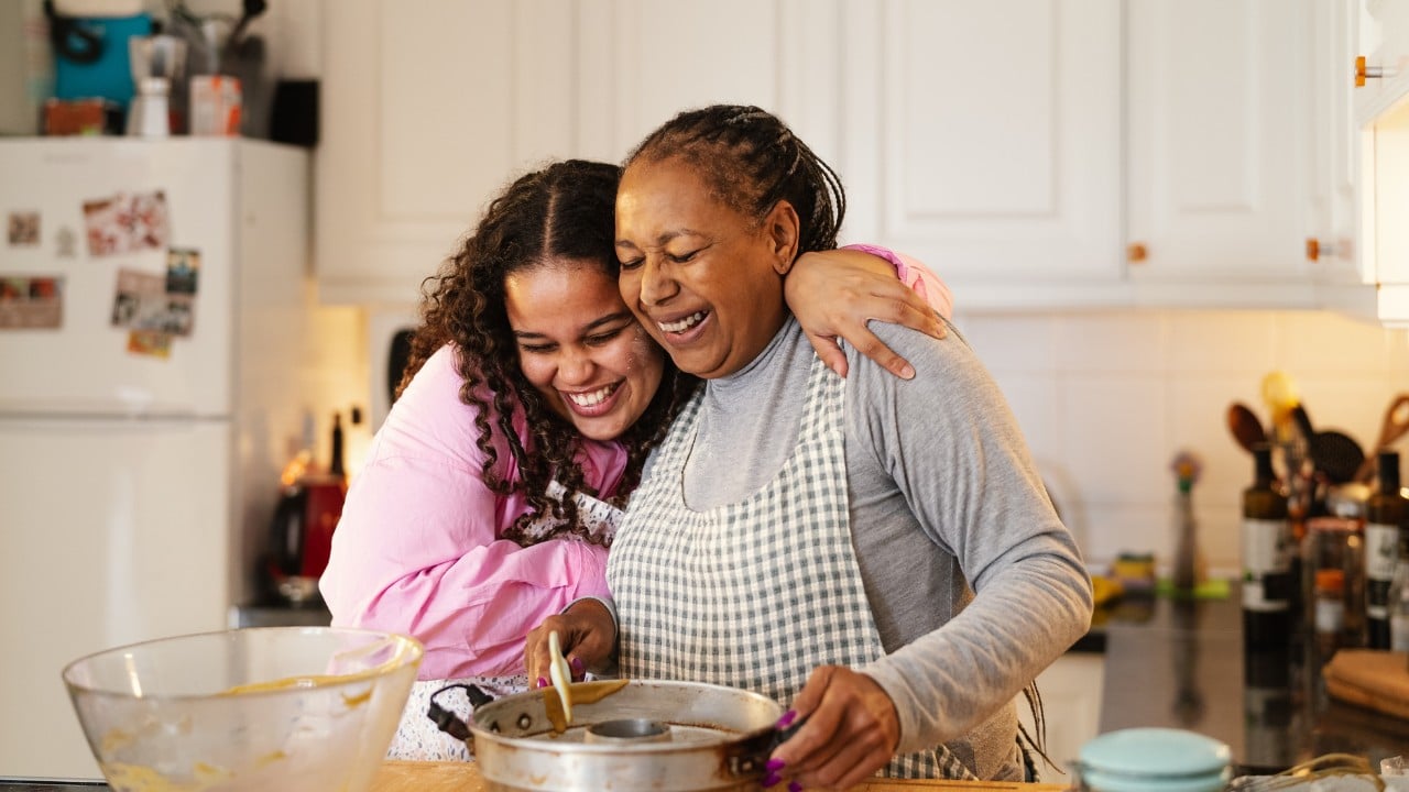 Happy african-american mother and daughter preparing a homemade dessert. They look very happy and joyful to be spending time together. Cooking, homemaking, dinner, family time, quality time, mother and daughter, positive influence, family bonding, feminine energy, black women, young and older, millennial and baby boomer, middle-aged woman, baking, cooking, preparing food.