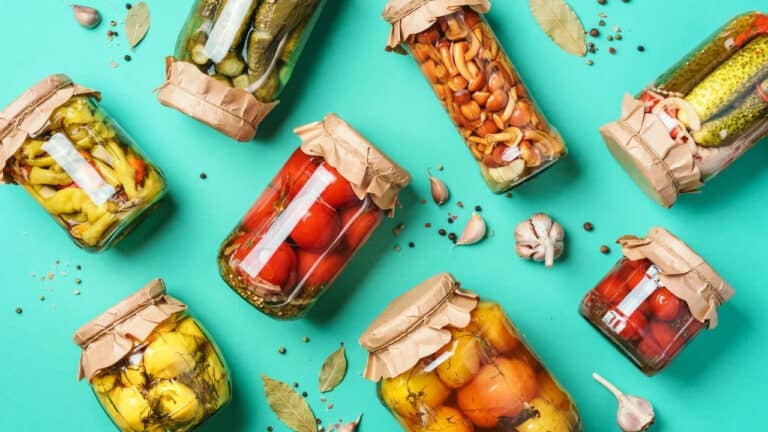 Featured image on 7/22/24. Stock Photo ID: 1570351972. Canned and preserved vegetables in glass jars over blue background. Top view. Flat lay.