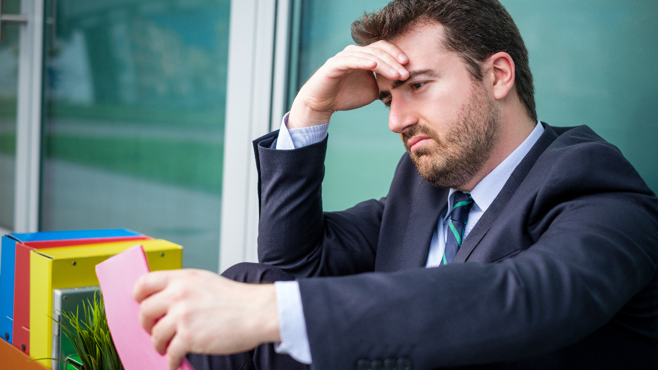 Man holding a pink slip looks disappointed