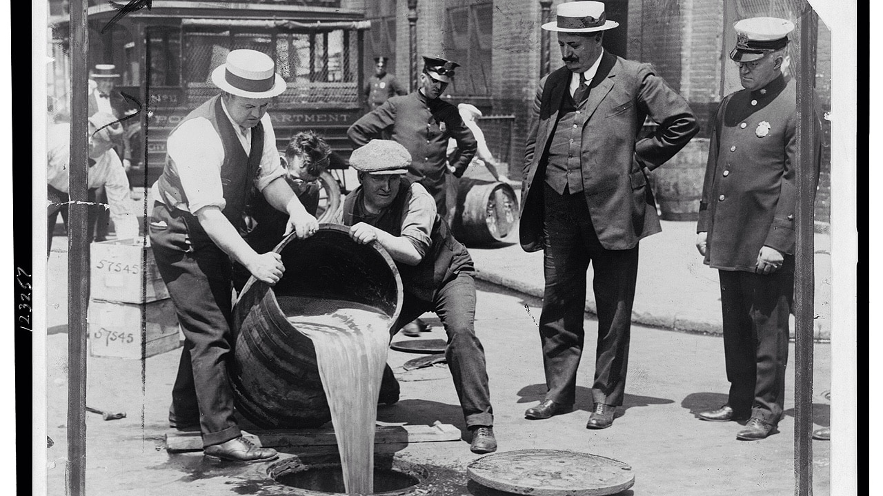 New York City Deputy Police Commissioner John A. Leach, right, watching agents pour liquor into sewer following a raid during the height of prohibition (1921)