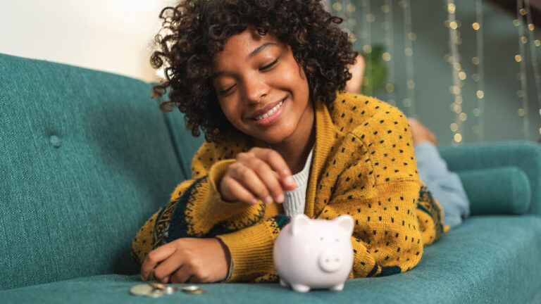 A kid putting money in their piggy bank