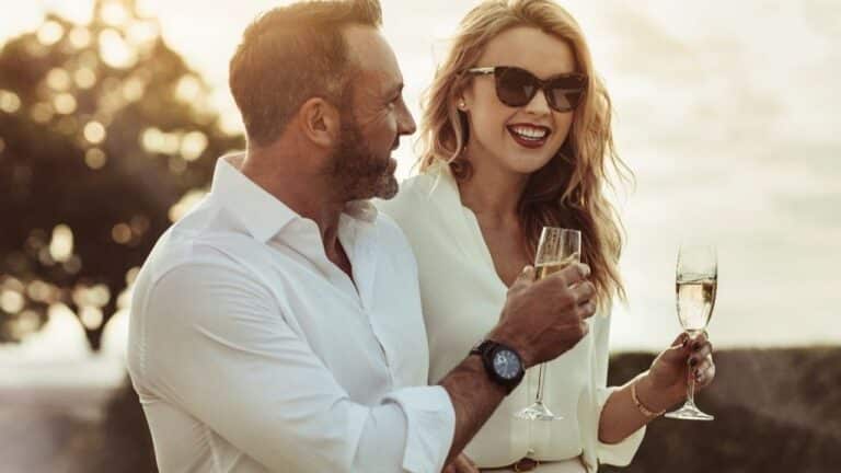 Smiling man and woman enjoying a glass of wine outdoors.