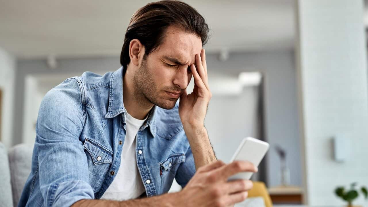 man using smart phone and holding his head, stress, worry, pain, headache, upset