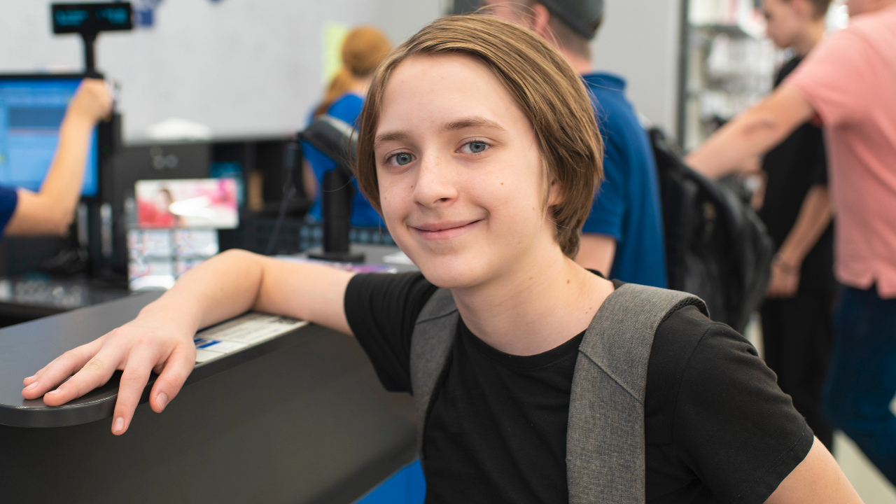 A teen stands in line at a store, ready to pay at check-out