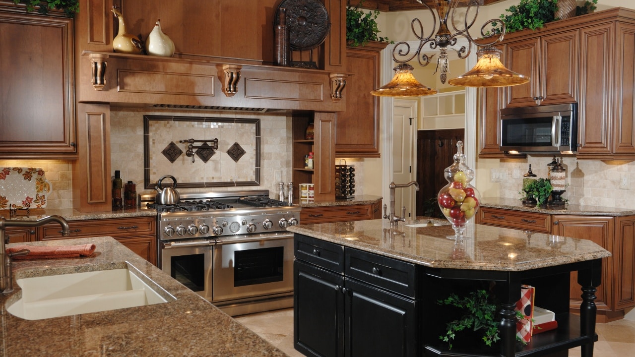An early 2000's tuscan-inspired kitchen, complete with tan granite countertops, cabinetry, backsplash and kitchen island.