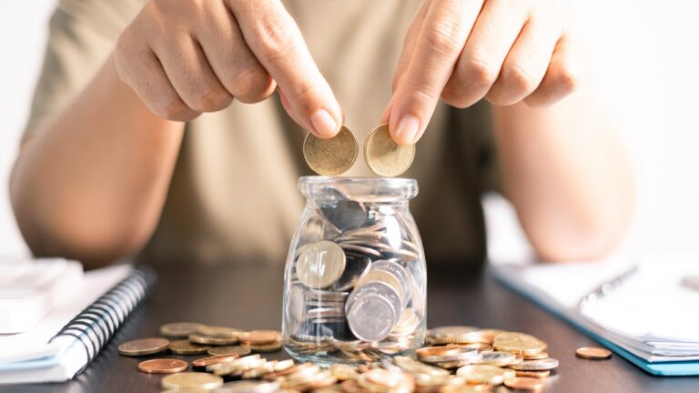 Putting two coins into a jar representing diversified savings