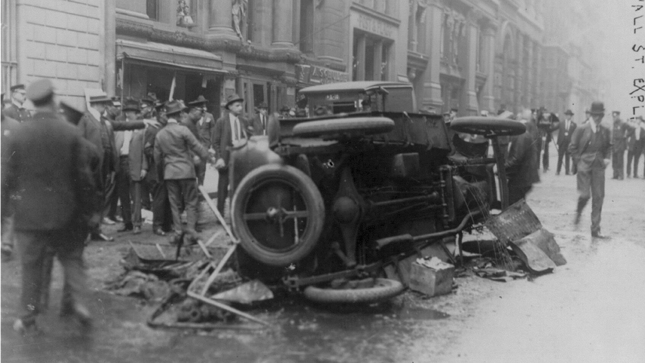 Wall Street explosion in 1920. Automobile lying on its side in foreground. A bomb exploded in front of the headquarters of J.P. Morgan Inc. at 23 Wall Street.