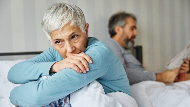 Portrait of unhappy senior woman or couple during or after arguing while sitting on bed