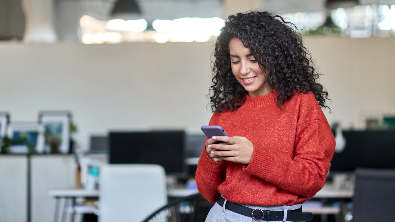 A young woman in an office searches for information on her smart phone
