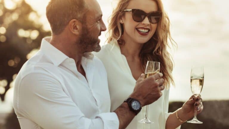 Smiling man and woman enjoying a glass of wine outdoors. Happy couple with a glass of wine sitting outdoors.