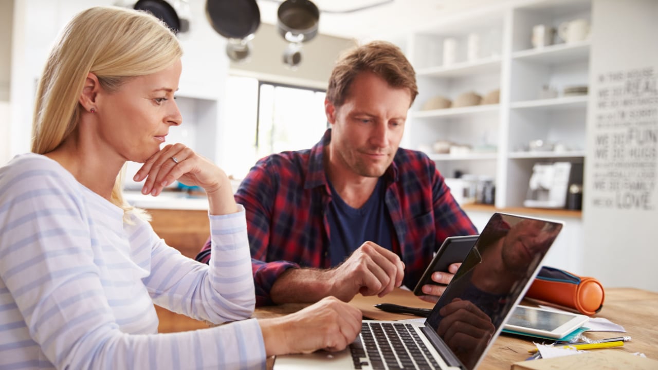 Man and woman researching, with laptop computer and cellphone.