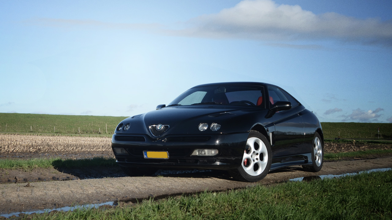 Alfa Romeo GTV, front 3/4 view, black exterior, sunny day, straight road