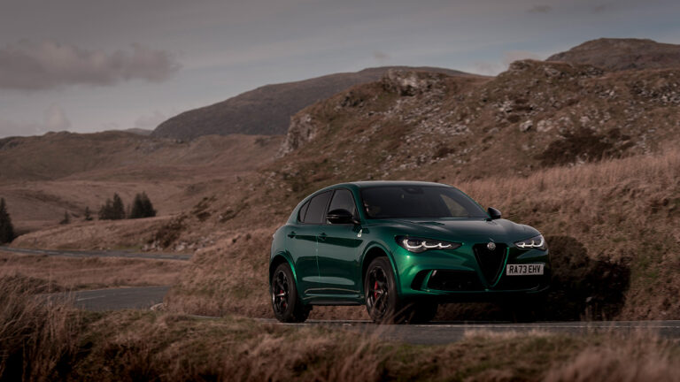 Alfa Romeo Stelvio Quadrifoglio, front 3/4 view, driving, mountain road, green, facelift