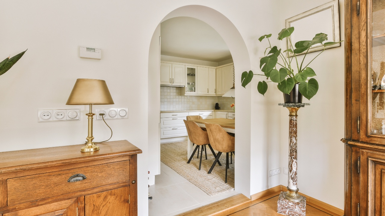 A living room with a dining table and an archway leading to the kitchen in the door is open on the side.