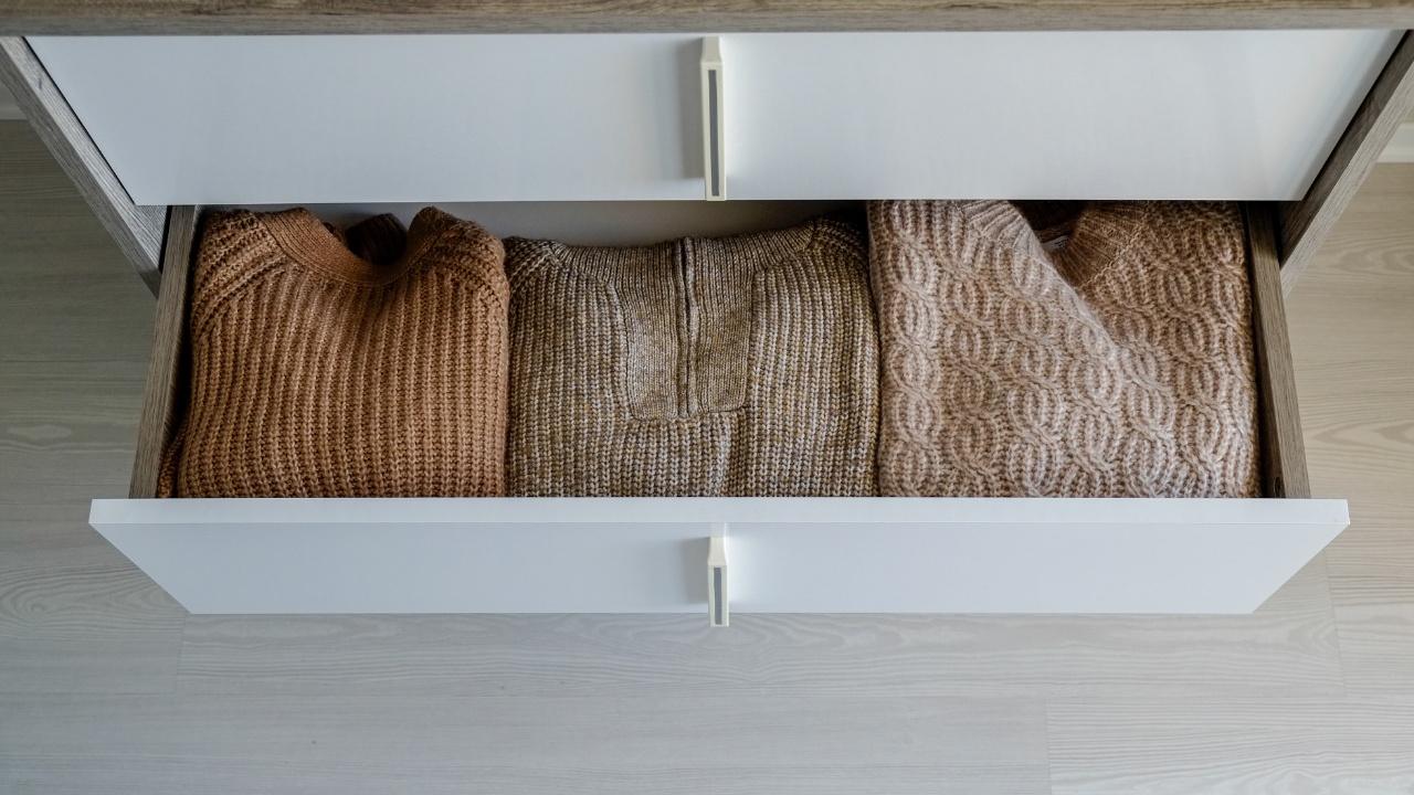 Close up shot of open drawers with neatly folded women's clothes inside.