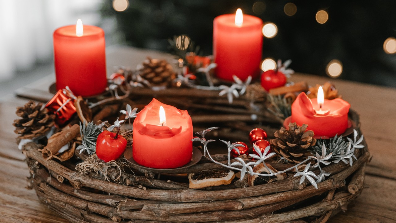 Female hand lighting the candles in an advent wreath table centerpiece.