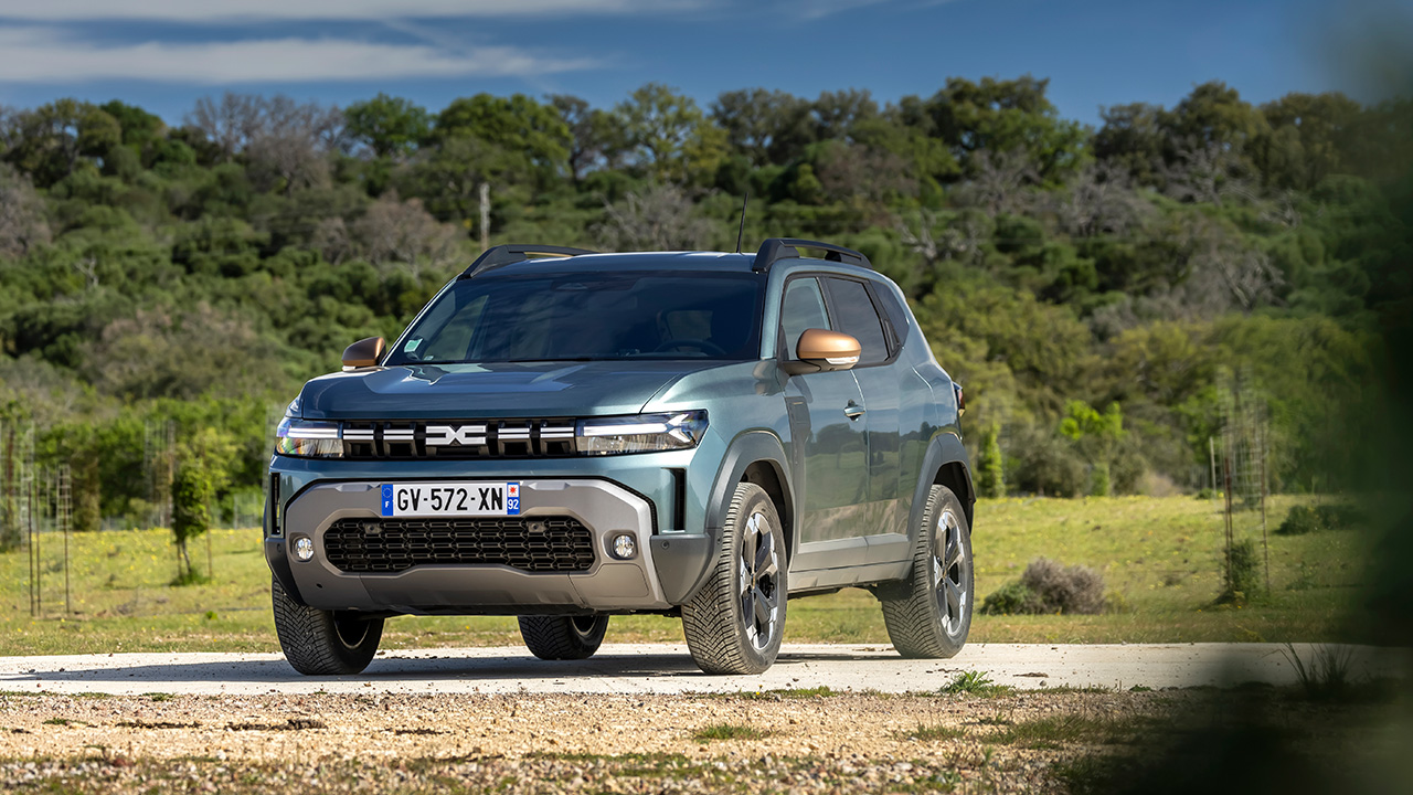 Dacia Duster, front 3/4 view, dark green, forest, dirt on bodywork.