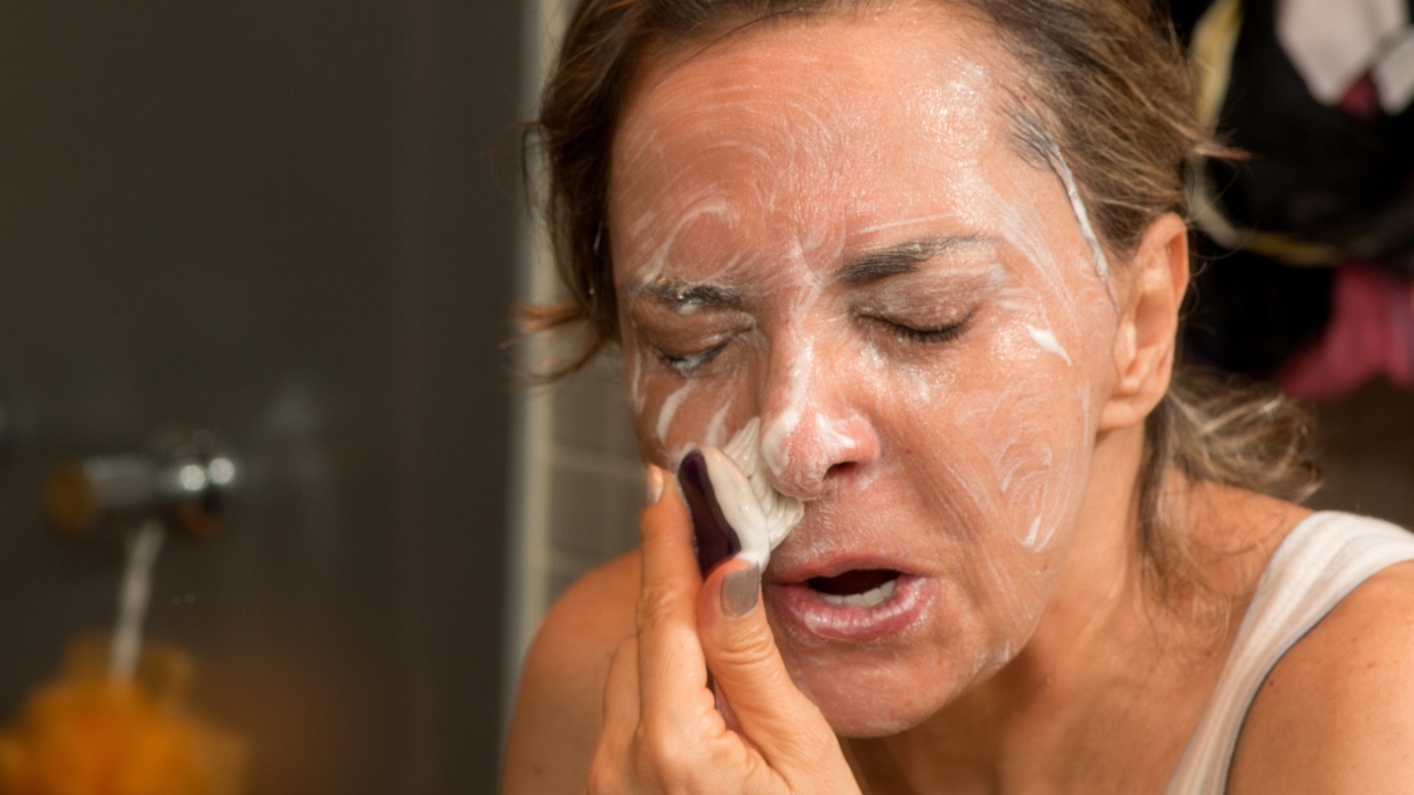 A woman scrubbing her face with a brush.