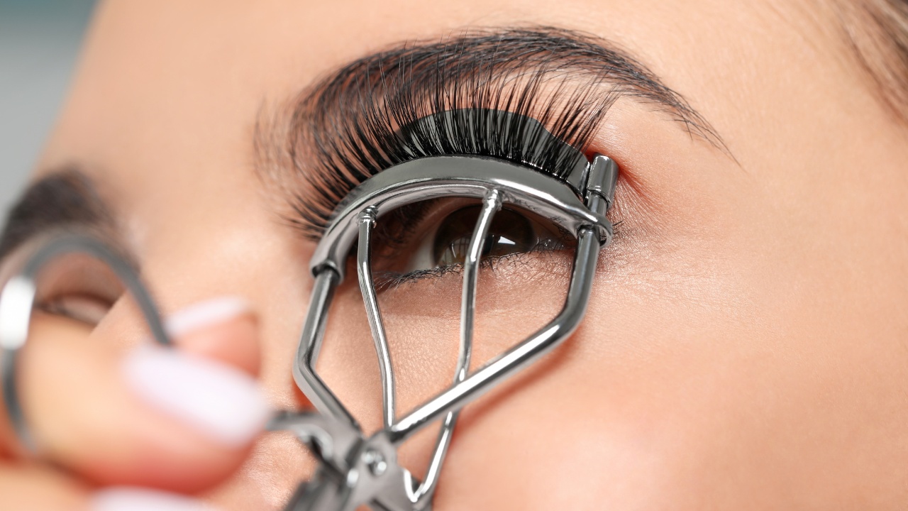 Young woman using eyelash curler, close-up.