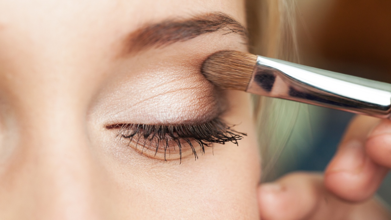 Close-up of a woman applying neutral-tone eyeshadow.
