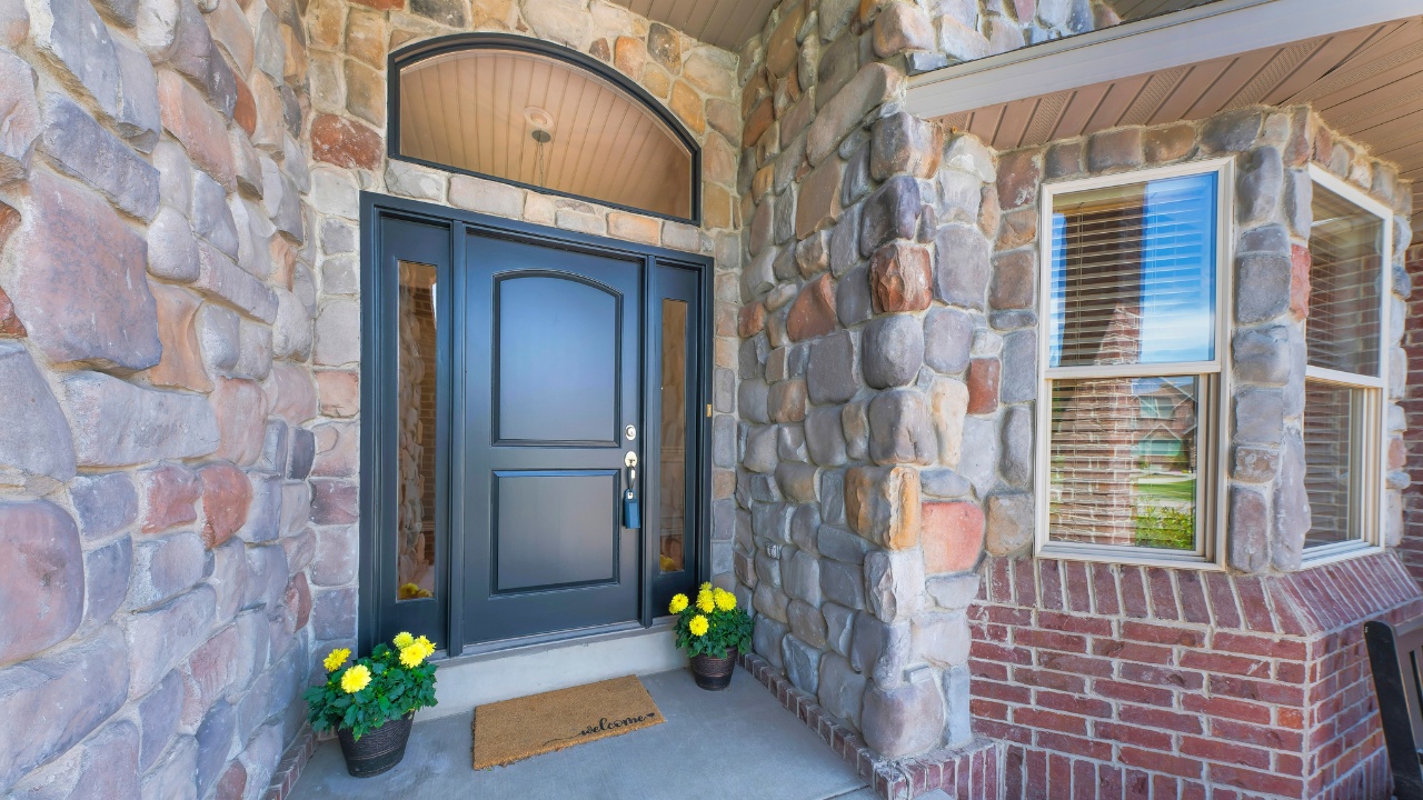 Green front door of a house with lockbox, transom window and two sidelights.