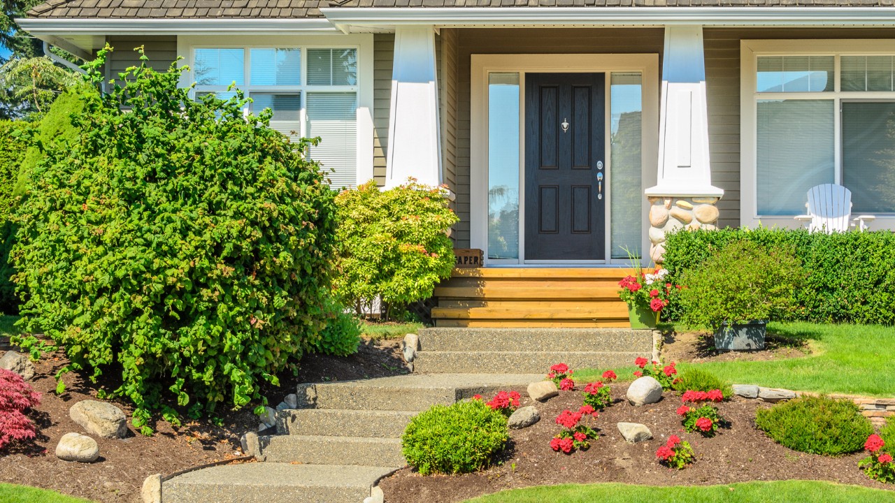 The front entryway of a modern suburban home with landscaping and stone on the outside of the home.