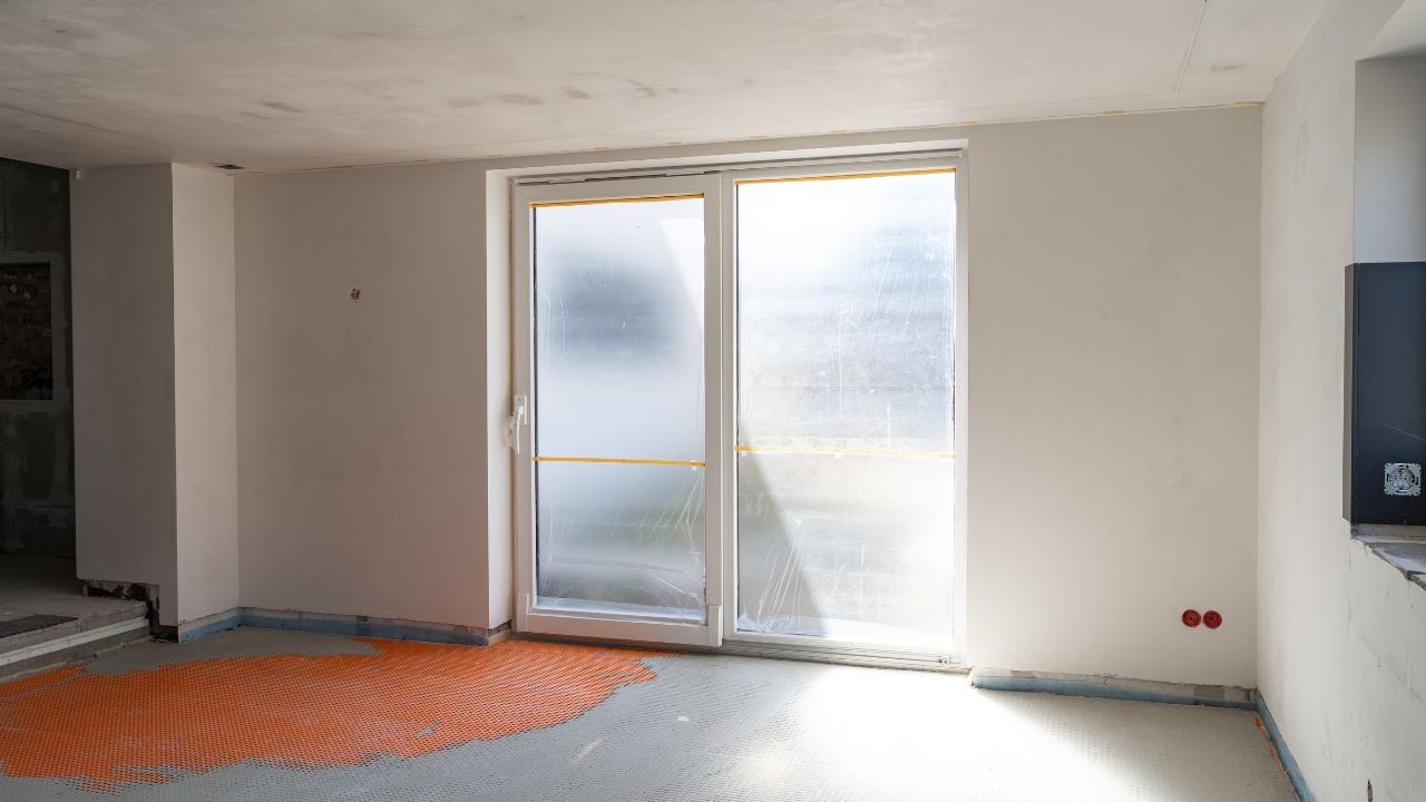 Unfinished Modern Kitchen Interior with Large Patio Door, White Walls, Orange Flooring Preparation, and Natural Light from Frosted Glass Windows