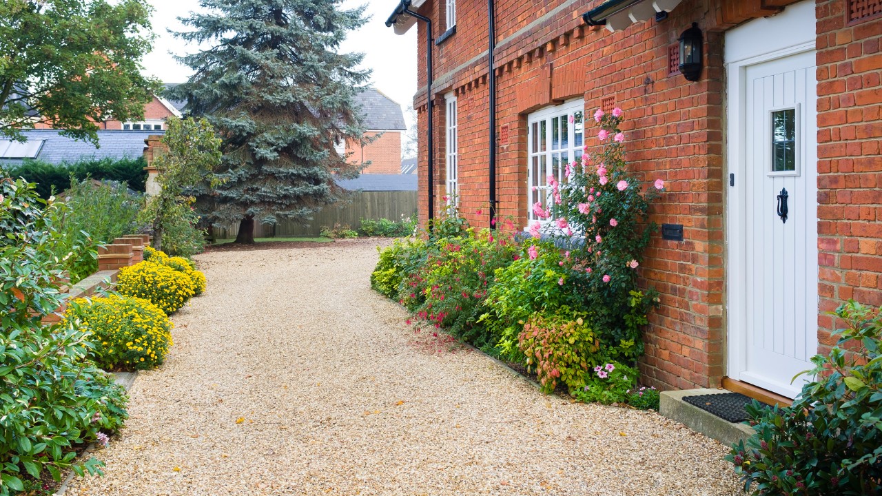 English country house and garden in Autumn with a gravel yard and driveway.