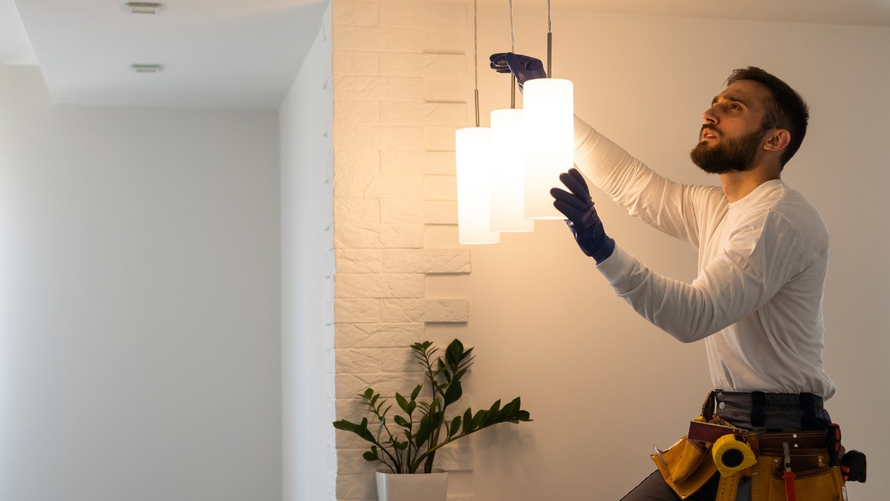 Electrician worker man assembling electric lamps in new apartment.