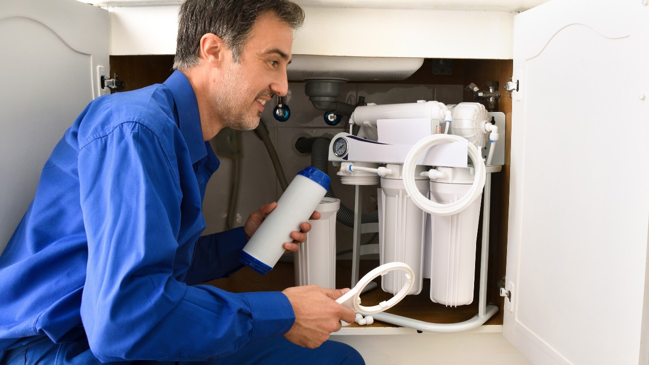 Technician installing reverse osmosis equipment under the sink.