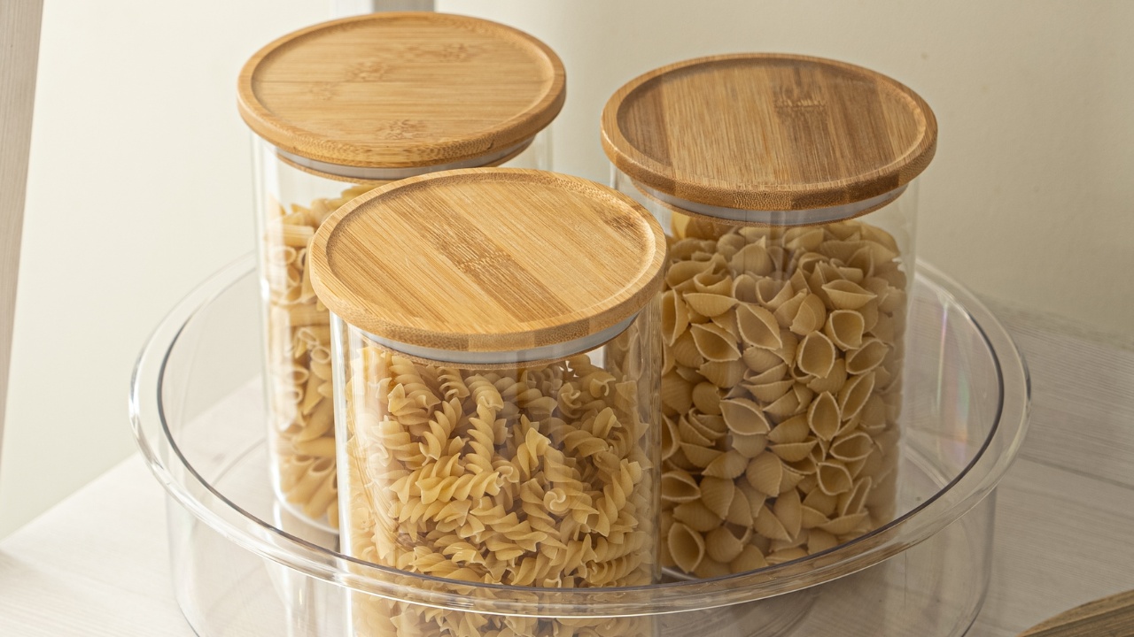 3 jars with bamboo lids in a clear acrylic lazy susan for cabinet organization.