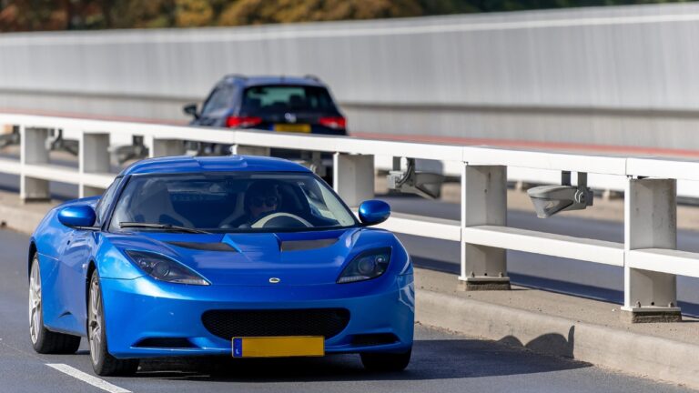 Front-side view of a blue Lotus Evora on the roadway.