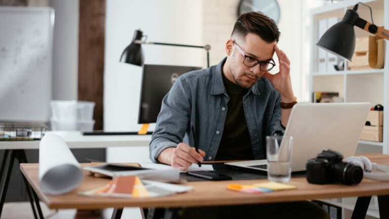 A man working at his computer desk in his home office.