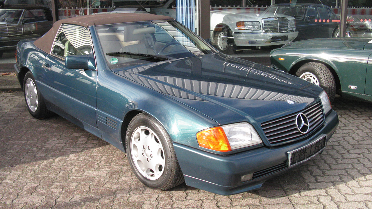 Mercedes-Benz SL, R129, front 3/4 view, sunny day, dealership, dark blue exterior, beige softtop
