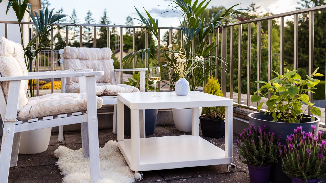 Beautiful cozy green balcony with potted plants, comfortable chairs and table for relaxing and enjoying nature at summer.