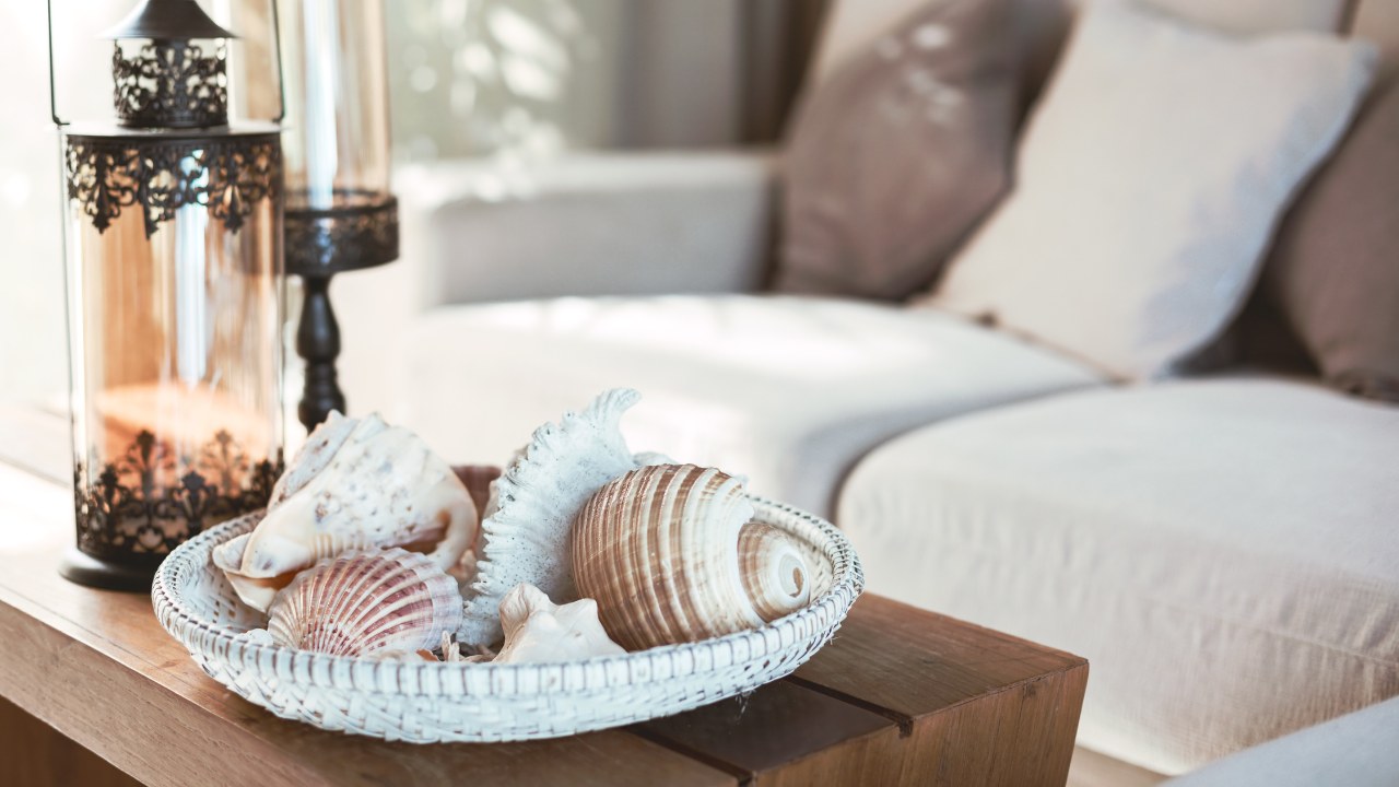 Beach interior decor: sea shells and lanterns on the wooden coffee table, natural colors. 