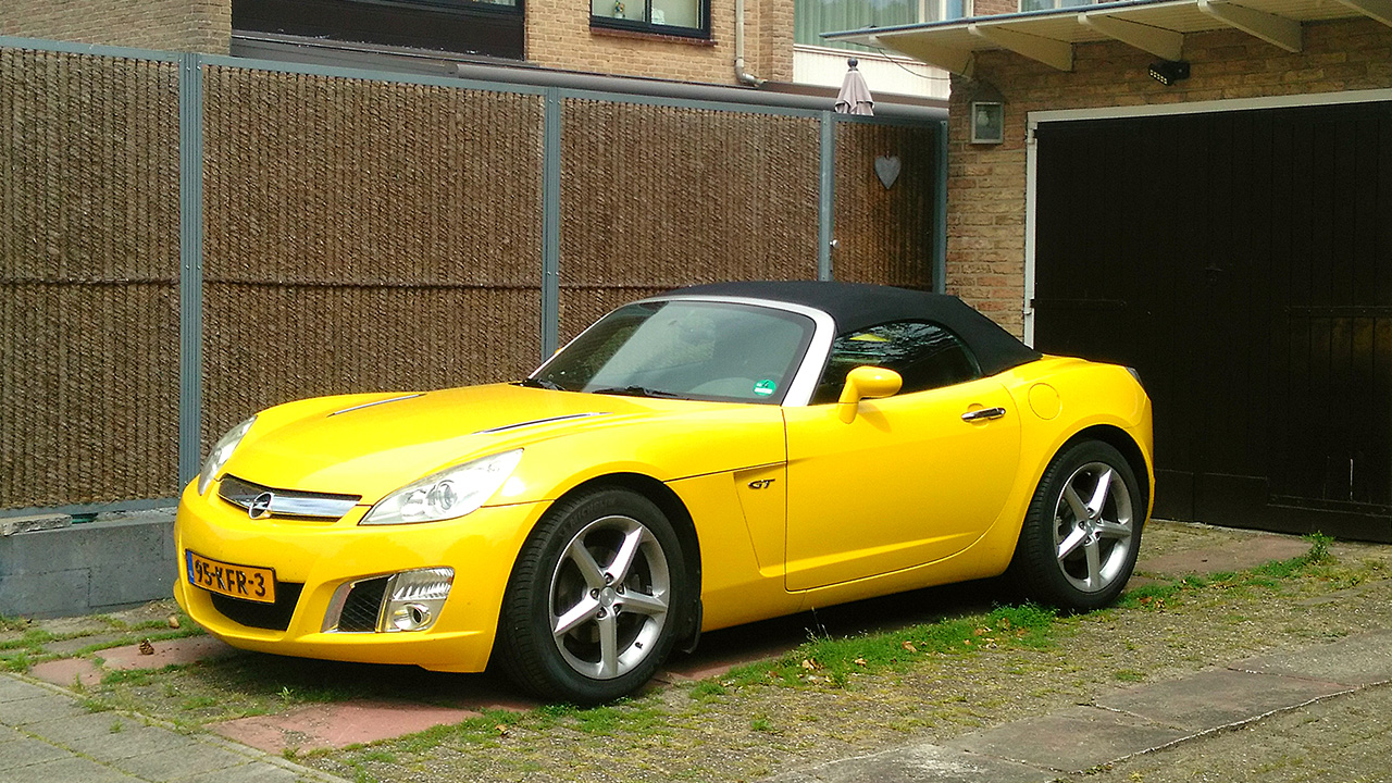 Opel GT, front 3/4 view, yellow exterior, roof up, driveway