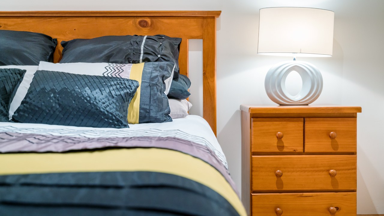Bedroom interior with bedroom setting including pine furniture, bedside table with lamp.
