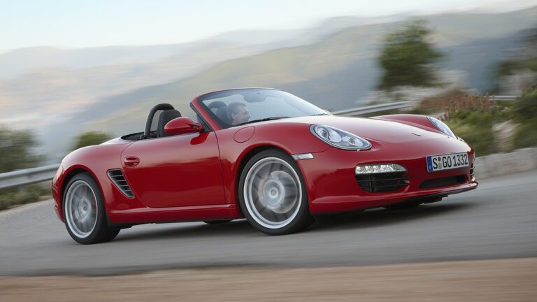 Porsche Boxster 987, front 3/4 view, red exterior, driving, roof down