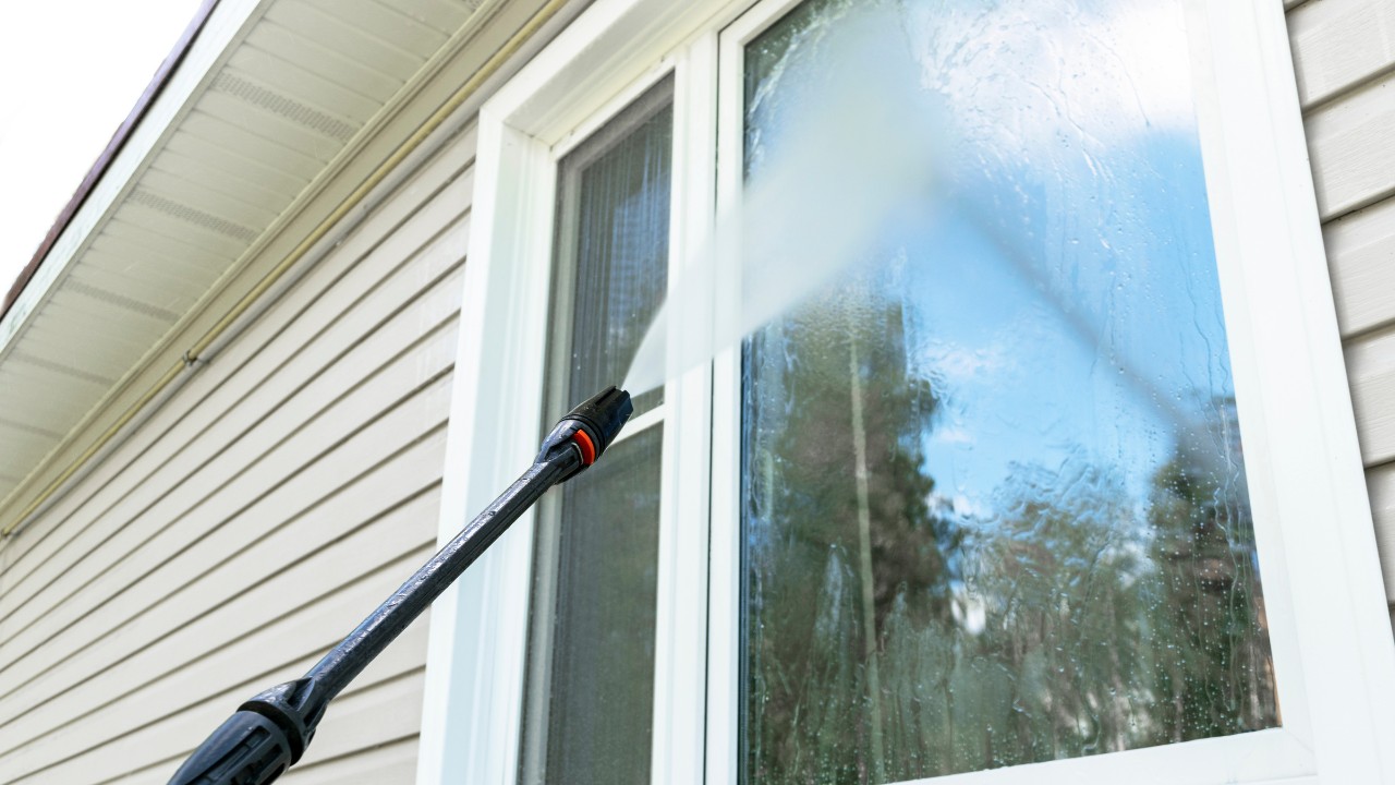 Cleaning service washing building exterior and window with pressure water.