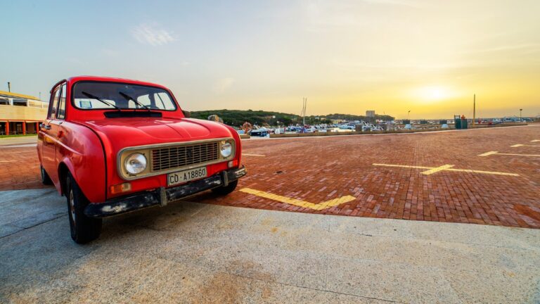 Red Renault 4 car parked in a street of the city center against sunset.