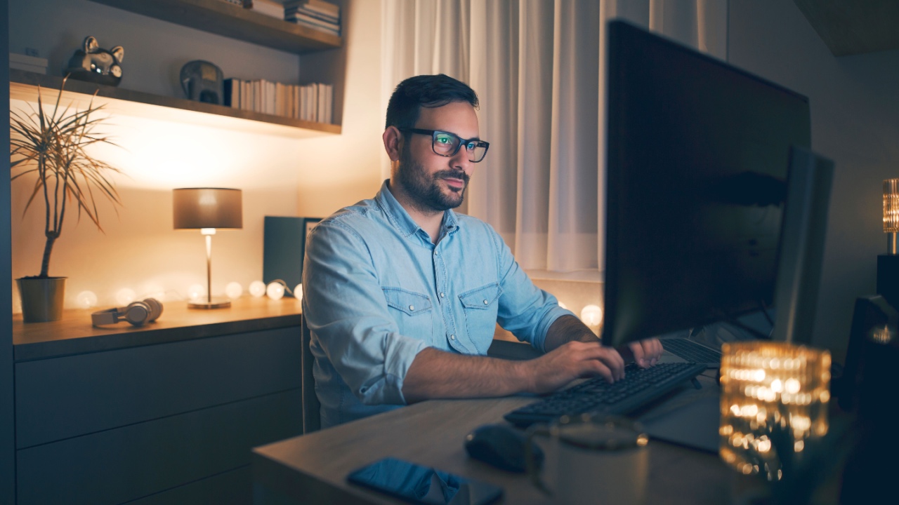 Modern young man working remotely from home at night.